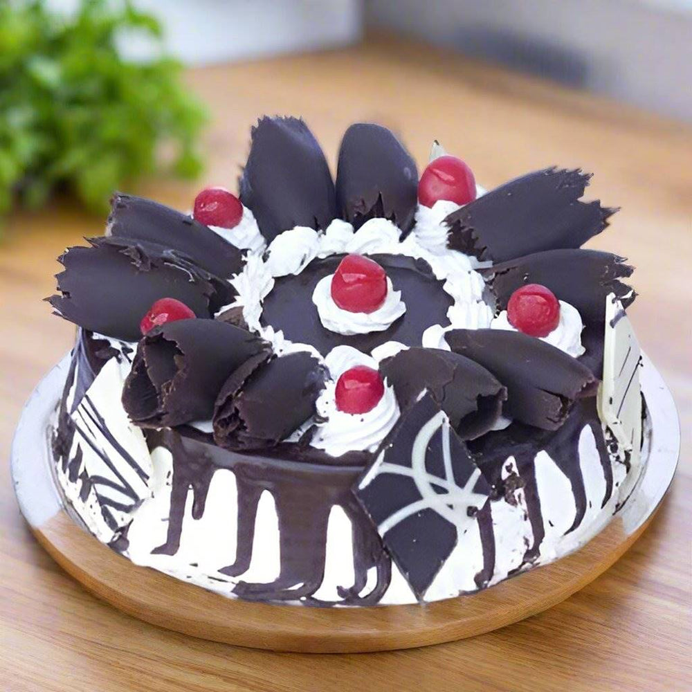 Black Forest Creamy Cake — white-and-dark piping with red fruit accents; India