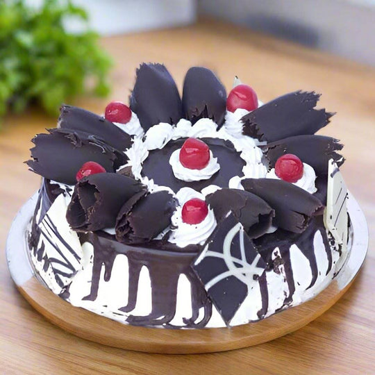 Black Forest Creamy Cake — white-and-dark piping with red fruit accents; India