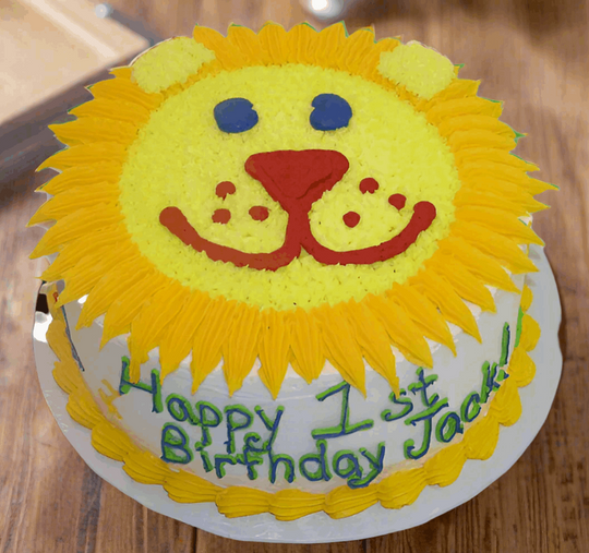 Cake Cartoon Theme — a bright yellow lion-face design and first-birthday lettering; India