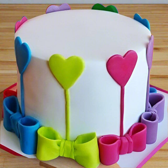 Colorful Ribbon Cake — white finish with colourful heart-and-ribbon-style decorations; India