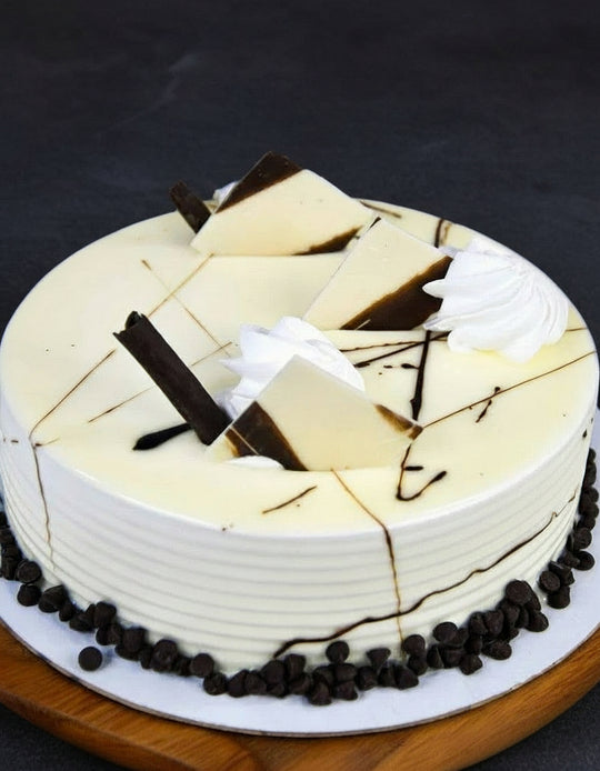 Chocolate Creamy Cake — white cream finish and pale decorative shards with dark drizzle; India