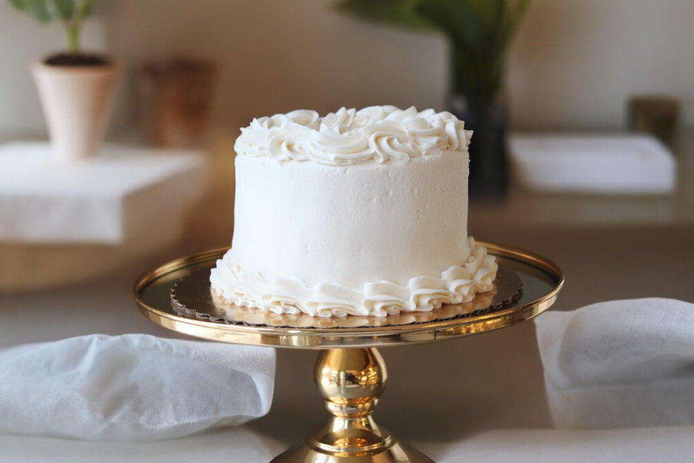 Elegant vanilla cake on a gold stand, perfect for UAE delivery