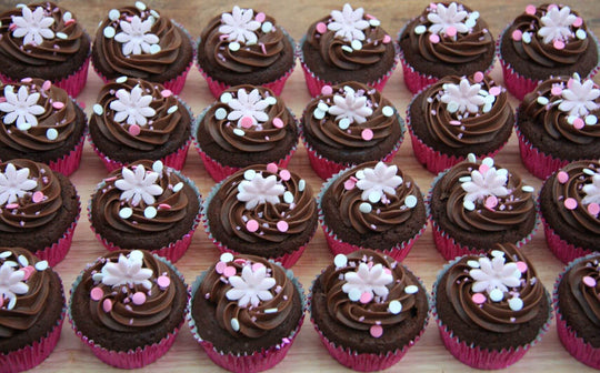 Flower Design Chocolate Cupcakes 24 Piece — dark frosting with small pale flowers and sprinkle accents; India