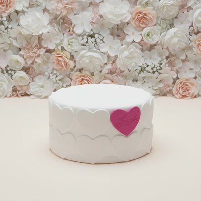 Elegant Cake — white finish, delicate side texture and a pink heart accent; India
