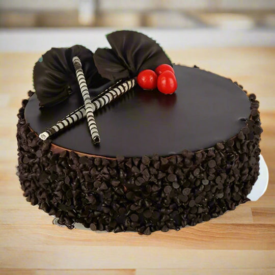 Birthday Chocolate Cake — dark crumb-covered sides, curled decorations and cherry accents; India