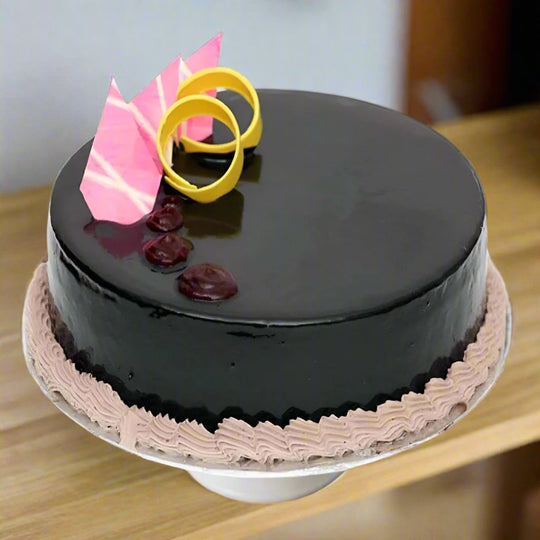 Round Smooth Finish Chocolate Cake — dark smooth finish with bright pink-and-gold topping accents; India