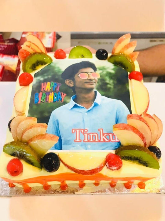 Photo Cake with Fruit Topping — a photo print surrounded by sliced fruit and cream; India