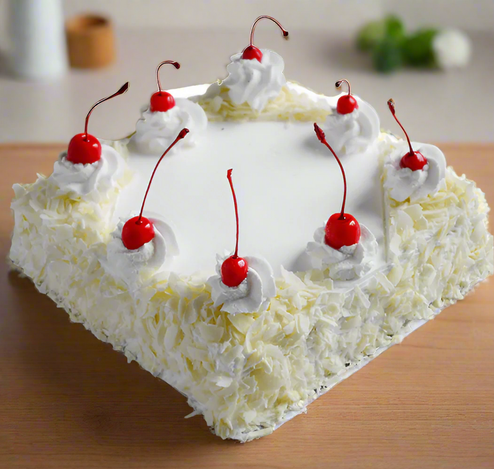 Creamy White Chocolate Cake — pale textured sides, white cream and red cherry topping; India