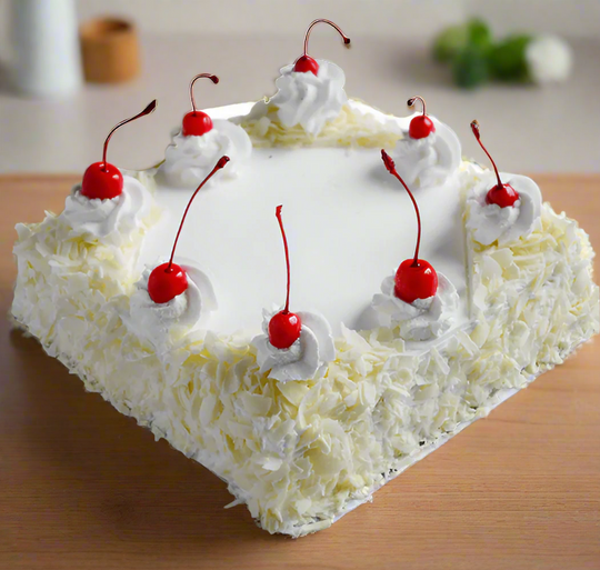 Creamy White Chocolate Cake — pale textured sides, white cream and red cherry topping; India