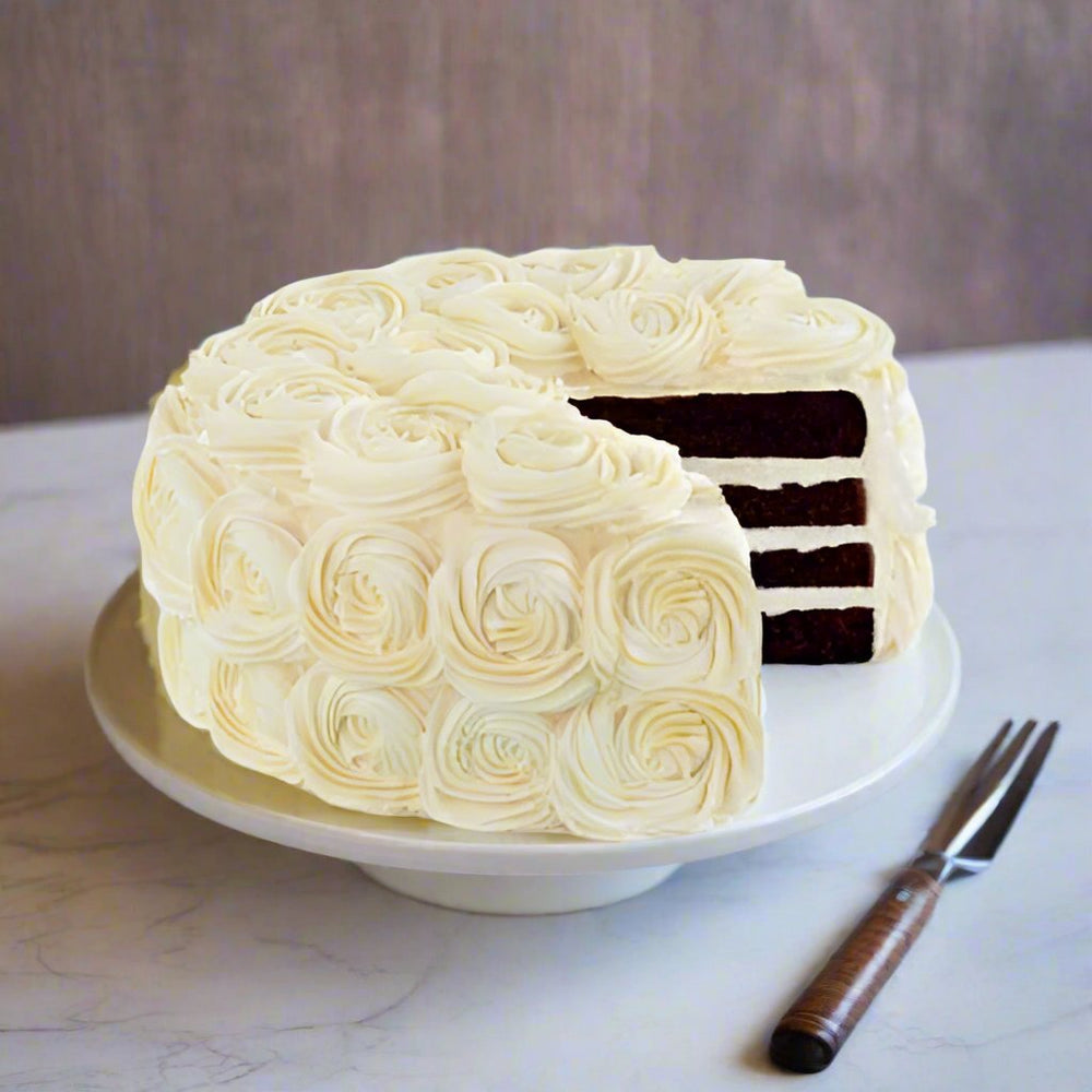 Flower Design White Chocolate Cake — white rose-style frosting with dark layers visible in the slice; India