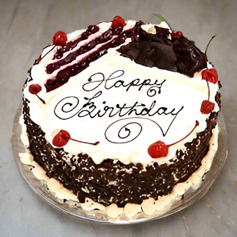 Black Forest Birthday Message Cake — white greeting centre, dark crumb sides and red cherry accents; India